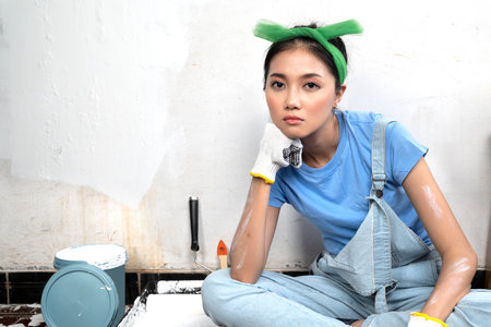 Asian young housewife in a glove with an unhappy expression with white wall backgroundの写真素材
