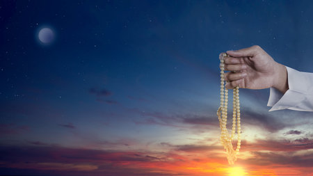 Muslim man praying with prayer beads in his hands with night scene backgroundの写真素材
