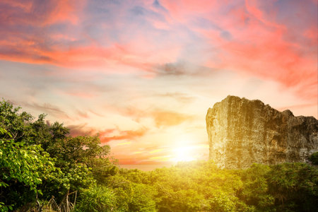 Rock hill and grass field with sunset sky backgroundの写真素材
