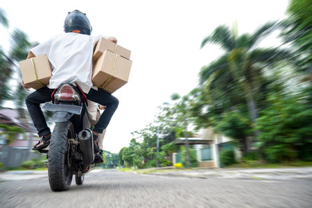 Rear view of Asian Muslim family carrying a box on a motorcycle going home to hometownの素材 [FY310199433373]