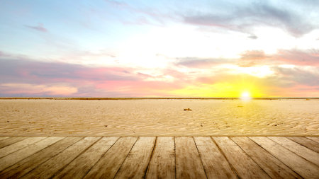 Wooden floor with views of sand dunes with a sunset sky backgroundの写真素材