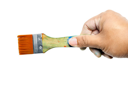 Human hand holding dirty paintbrushes isolated over white backgroundの写真素材