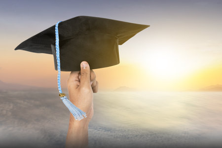 Graduates student holding graduation caps with the sunset scene backgroundの写真素材