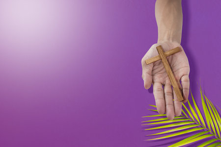 Human hand holding Cross with a palm leaf. Palm Sunday Conceptの写真素材