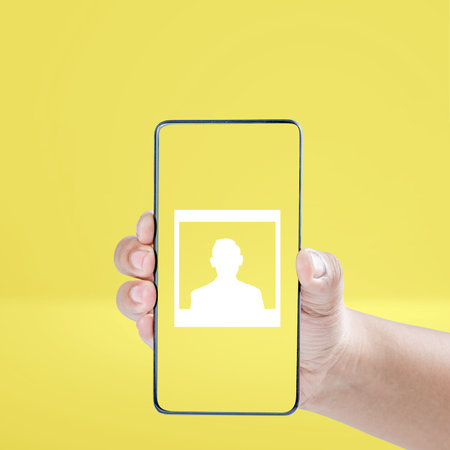 Human hand holding mobile phone screen with photo symbol on a colored backgroundの写真素材
