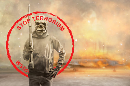 A man wearing a mask holding a gun with a stop terrorism sign with a fire backgroundの写真素材