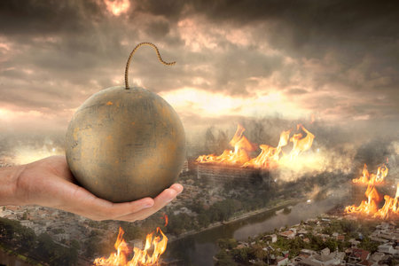 Human hand holding ball bomb with ruined city backgroundの写真素材