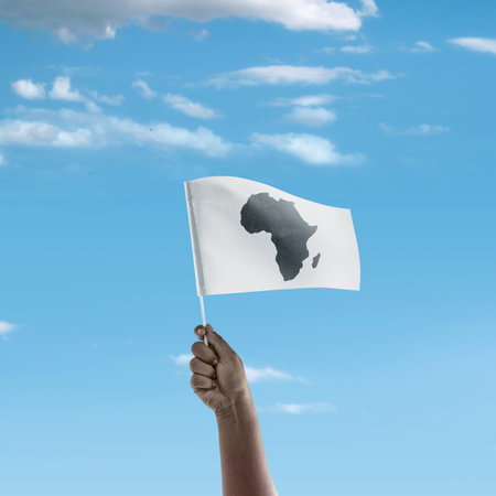 A human hand holding a Flag with African maps with a blue sky background. Africa day conceptの写真素材