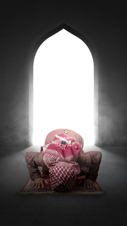 Muslim man with a beard wearing keffiyeh with agal in praying position (salat) on the prayer rug inside the mosqueの写真素材
