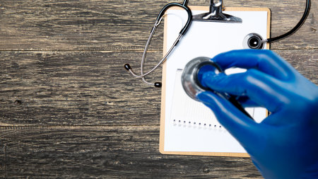 A human hand holding a stethoscope and an empty notebook. World hypertension day concept
