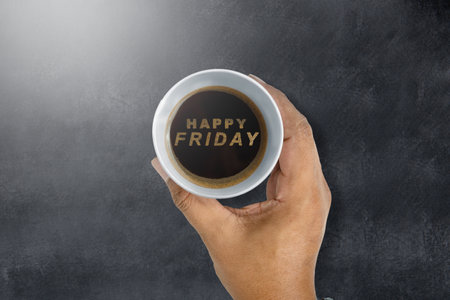 A human hand holding a coffee cup with a Happy Friday text. Happy Friday conceptの写真素材