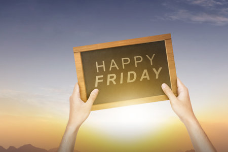 A human hand holding a blackboard with a Happy Friday text. Happy Friday conceptの写真素材