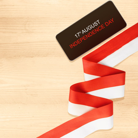 Mobile phone with Indonesian independence day message on the screen with a red and white flag ribbon. Indonesian independence dayの写真素材