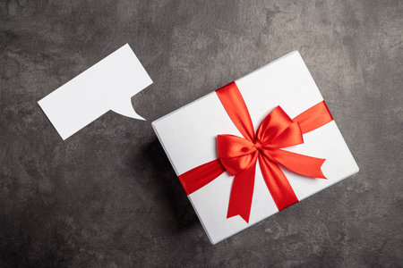 Empty paper with speech symbol and gift box on black background. Empty area for copy spaceの写真素材