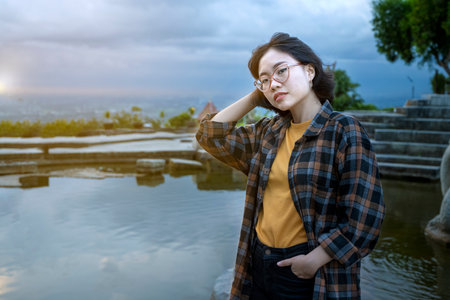 Asian woman standing with pond and sunset scene background