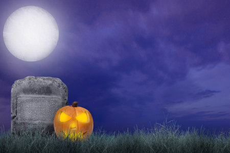 Jack-o-Lantern on a tombstone in the graveyard with a night scene background. Scary Halloween background conceptの写真素材