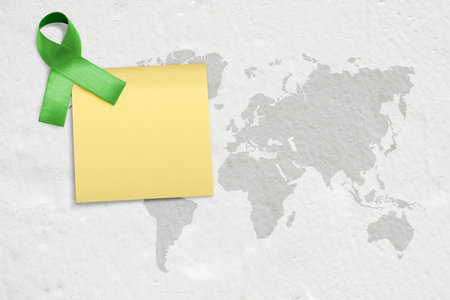 Worldwide map with green ribbon and empty paper for copy space. World mental health day conceptの写真素材