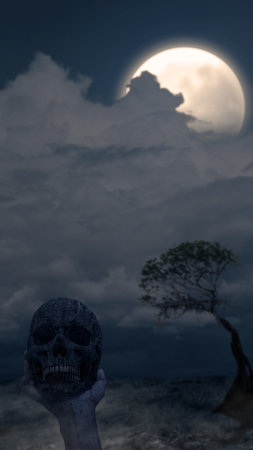 Hand holding human skull head with night scene background. Scary skull Halloween conceptの写真素材