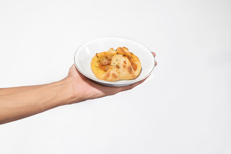 A human hand holding a side dish on a plate with a white backgroundの写真素材