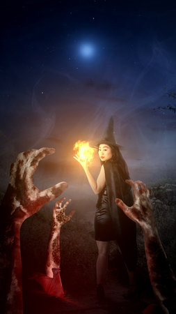 Scary witch showing magic spell on her hands with rising zombie hands. Scary witch for Halloween. Halloween conceptの写真素材