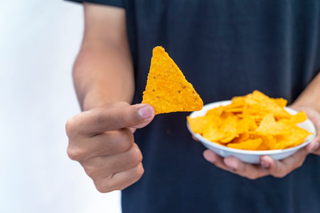 A human hand holding a plate with tortilla chips with a white backgroundの写真素材