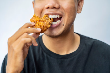 Man eating fried chicken with a white backgroundの写真素材