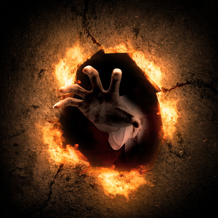 Zombie's hand on the hole with a fire flames background. Scary Halloween concept