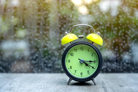 Alarm clock on the table with a clear window and raindrop backgroundの写真素材