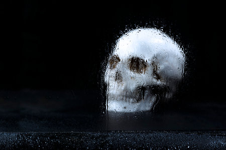 Human skull head with water drop in window in a dark background. Scary skull Halloween conceptの写真素材