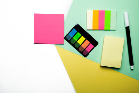 A colorful sticky note and notepaper with marker on a colored background
