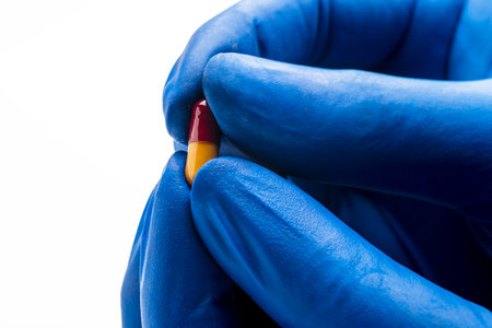 Hand with medical glove break the pill isolated over white backgroundの写真素材