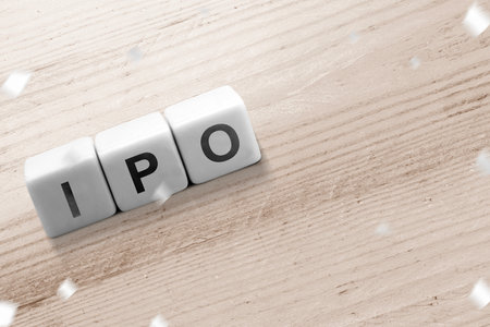 A row of small cubes with IPO letters on a wooden table. Stock investment concept