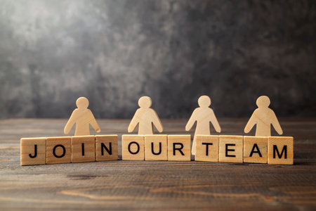 Wooden figures and wooden cubes with Join Our Team letters on a wooden table. Human resources...