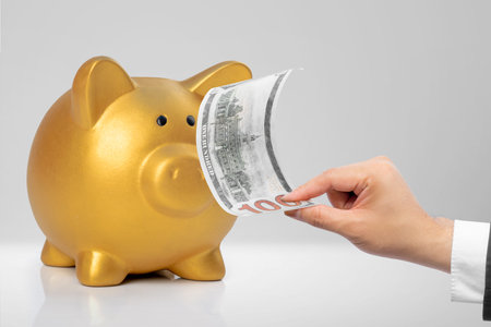A human hand holding a money with piggy bank on a white table. Financial conceptの写真素材