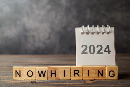 2024 calendar and wooden cubes with Now Hiring letters on a wooden background. Looking for a new job on new year. Human resources management concept.の写真素材