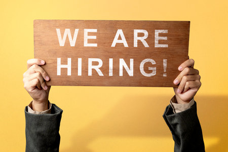 The businessman's hand shows the wooden board with We Are Hiring letters. Human resources management conceptの写真素材
