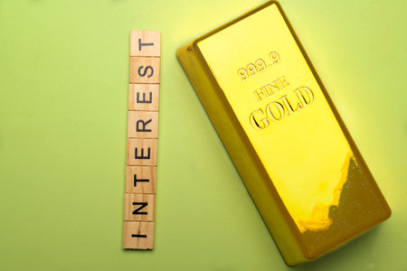 Closeup view row of wooden cubes with Interest letters and gold bar on a colored background. The financial and economic conceptの写真素材