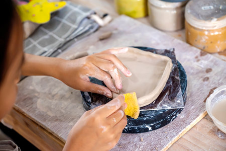 Closeup view of kids making a craft of a porcelain mug from wet clay. Pottery craft clay concept