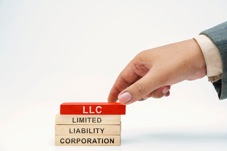 Business hand put wooden block stack with LLC - Limited Liability Company text on white background. Business conceptの写真素材
