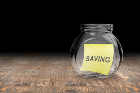 Glass jars with saving text in notepaper on the table. Financial saving conceptの写真素材