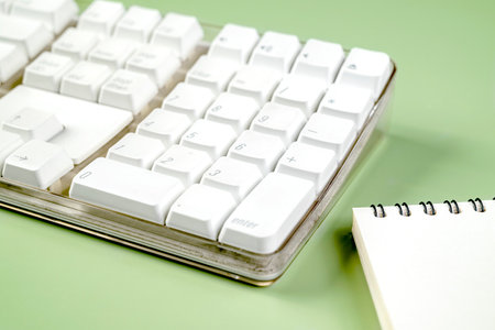 Closeup view of a computer keyboard with an empty notebook on a colored background. Empty notebook for copy spaceの写真素材