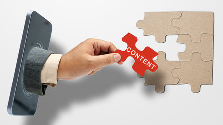 Business hand coming out from mobile phone screen and showing content text on a piece of jigsaw puzzle. Content manager, strategy and creativity conceptの写真素材