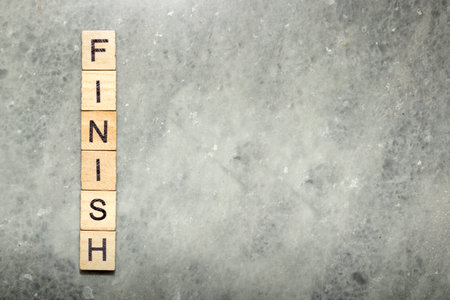 A row of wooden cubes with finish text over a gray background. Business and success conceptの写真素材