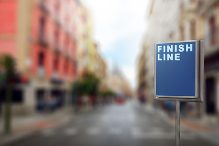 A sign pole with finish line text over a blurred background. Business and success conceptの写真素材