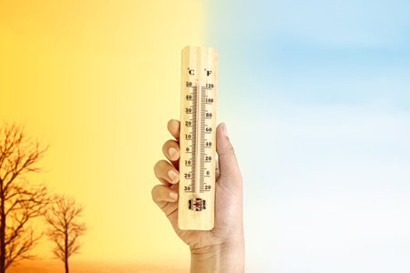 Human hand holding thermometer with a high heat temperature with a different sky background....