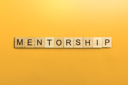 The row of wooden cubes with 'mentorship' text on a colored background. Mentorship concept