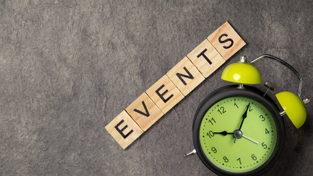 The row of wooden cubes with 'events' text and alarm clock on a black background. Event planning conceptの写真素材