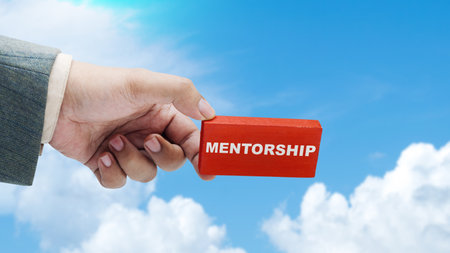 Business hand holding a wooden block with 'mentorship' text. Mentorship conceptの写真素材
