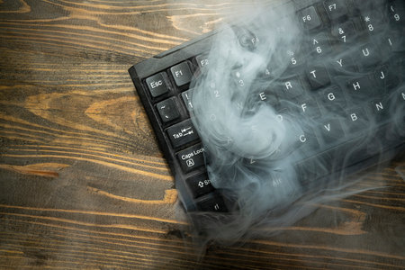 Closeup view of a computer keyboard with white smoke on a wooden backgroundの写真素材