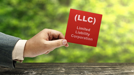 Business hand holding a note with LLC text, the acronym of Limited Liability Company. Business...